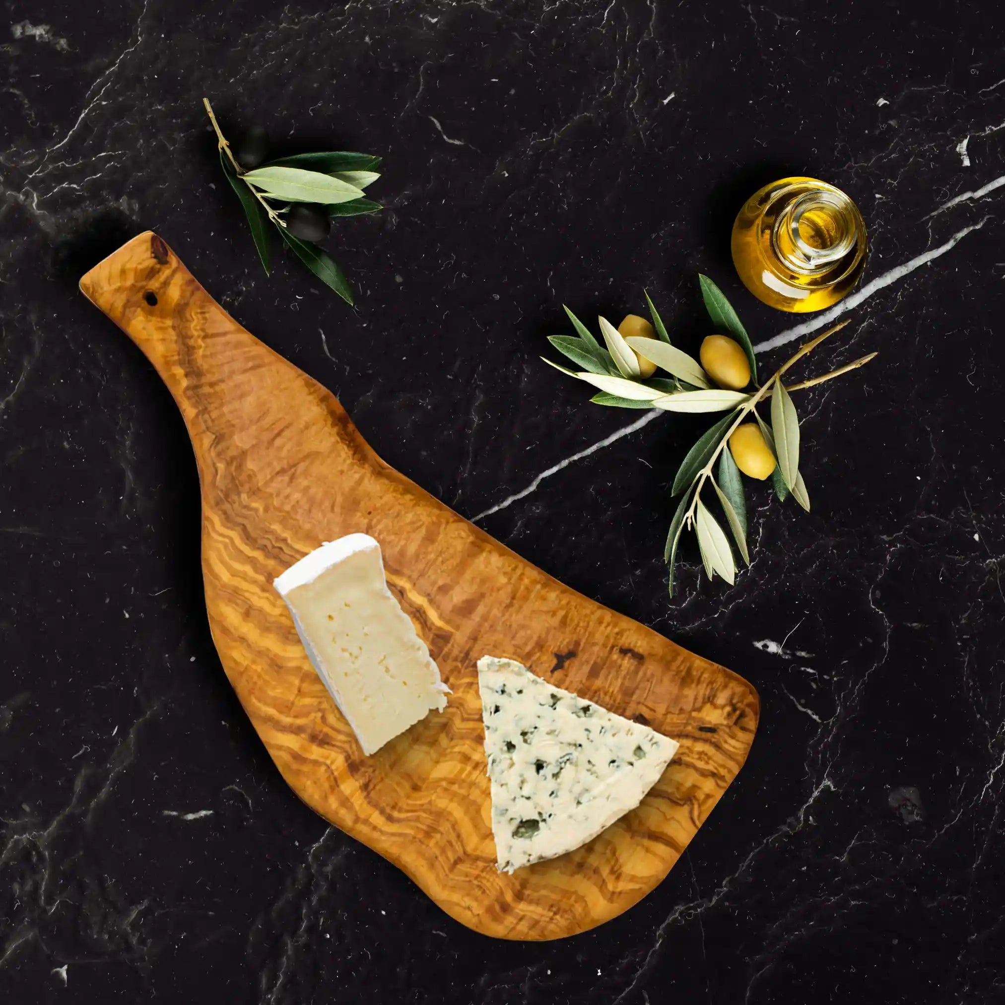 A handcrafted olive serving board displayed on a rustic dinning table.