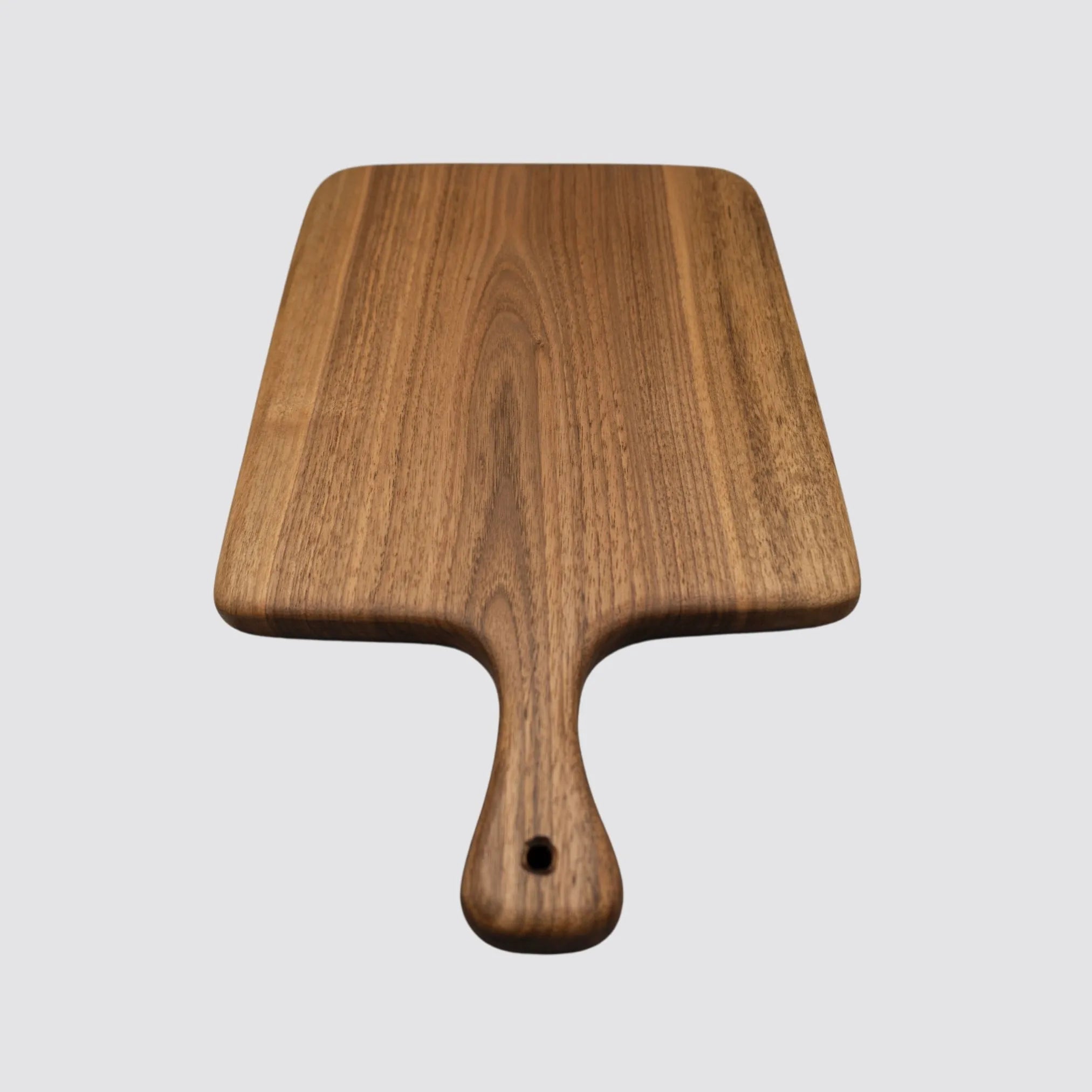 Elegant walnut cutting board displayed on a light gray background, focusing on its natural beauty.