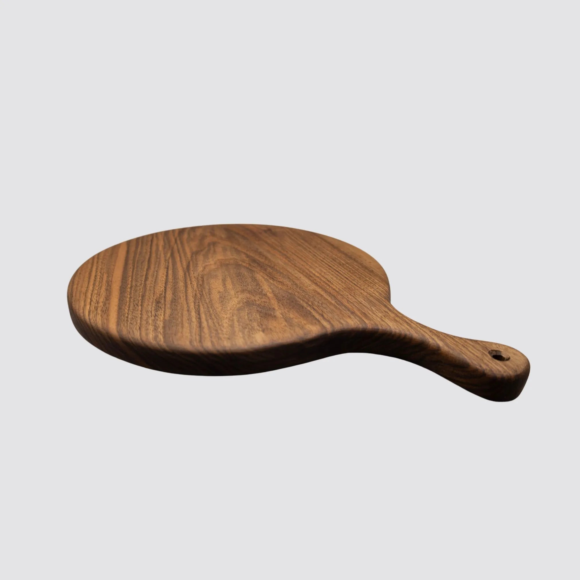 Side profile of a handcrafted walnut charcuterie board, emphasizing the rich wood grain and handle design.