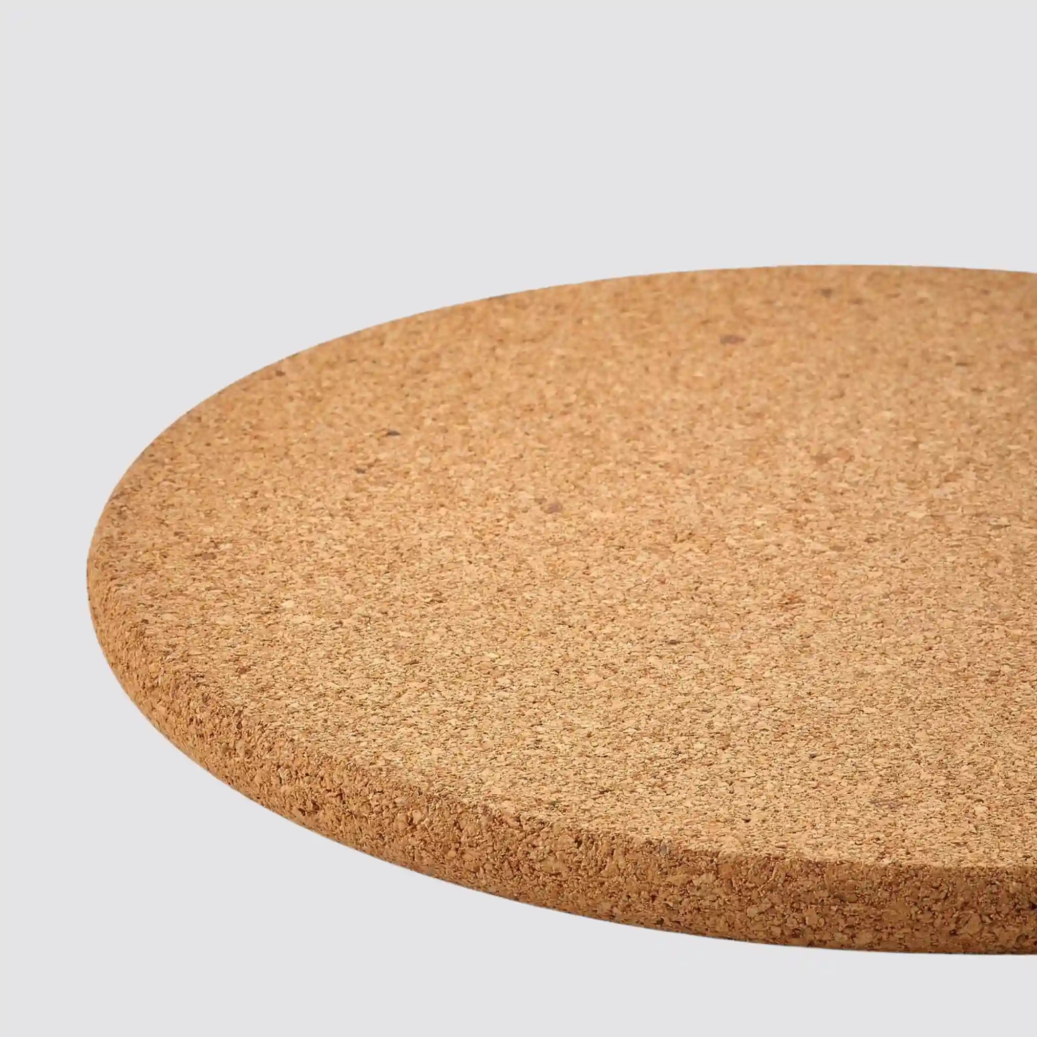 Close-up of a heat-resistant round cork placemat on a plain background.