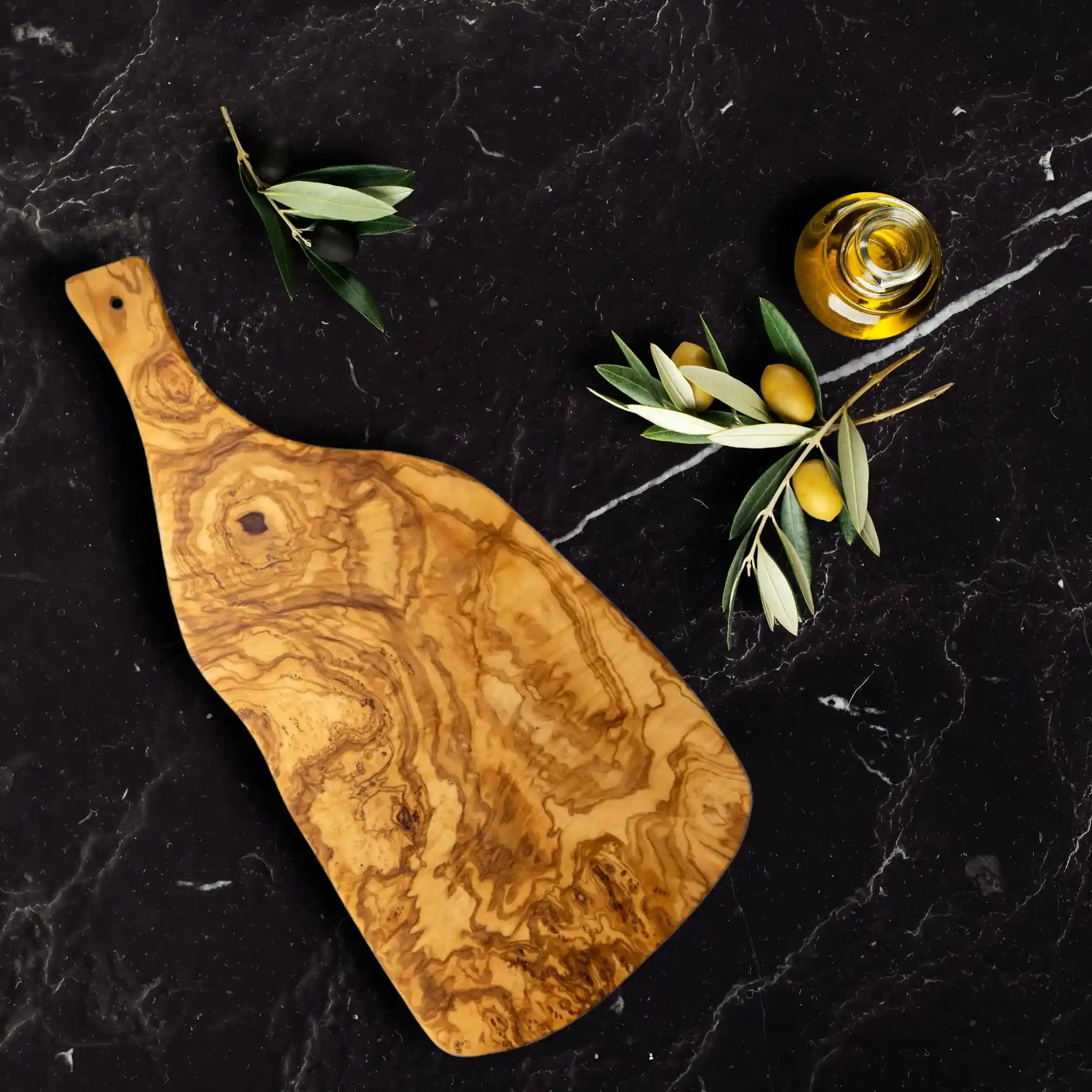 The large charcuterie serving board made of sustainable olive wood is displayed on a luxury dining table.