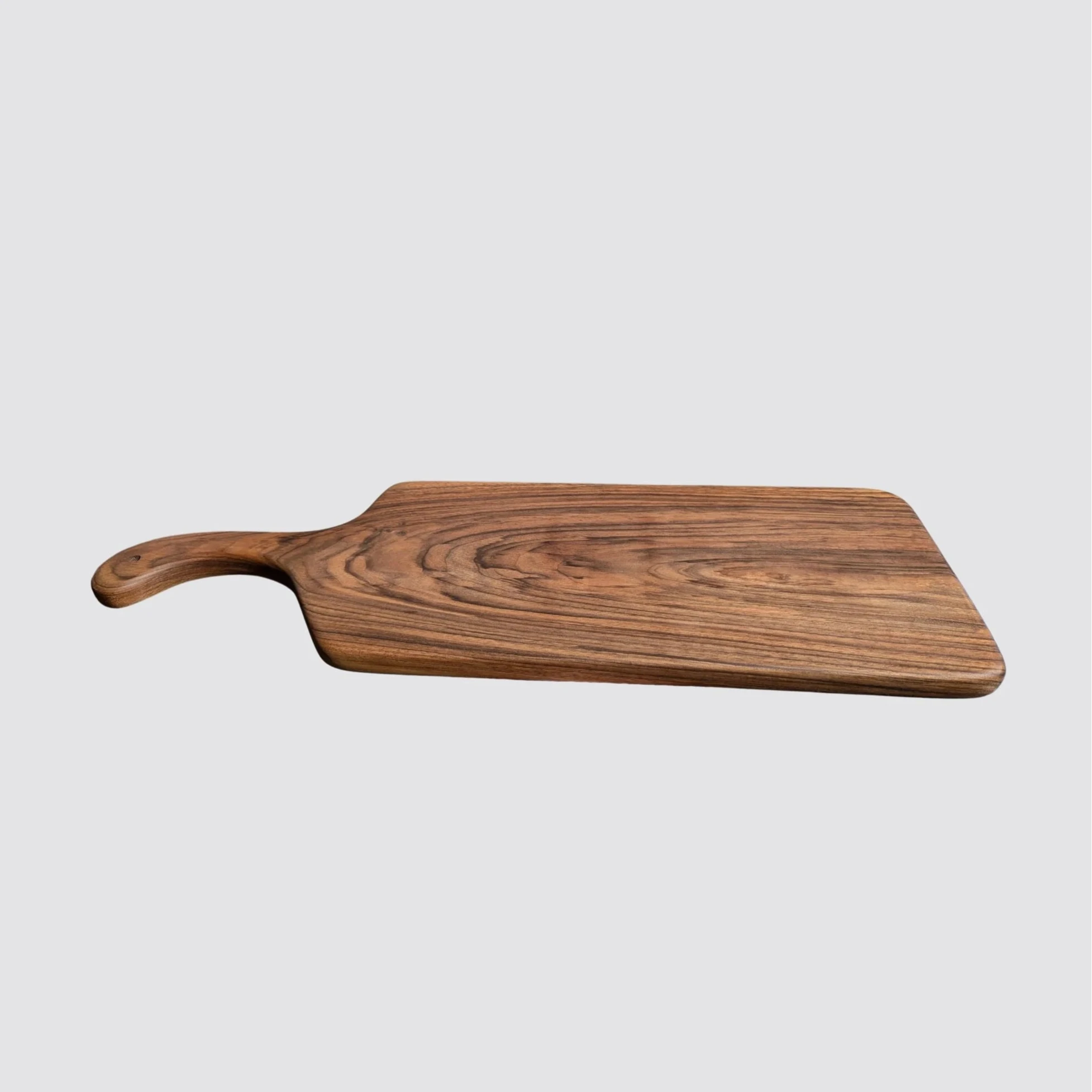 A handcrafted long walnut charcuterie board with a handle, showcasing its natural wood finish.