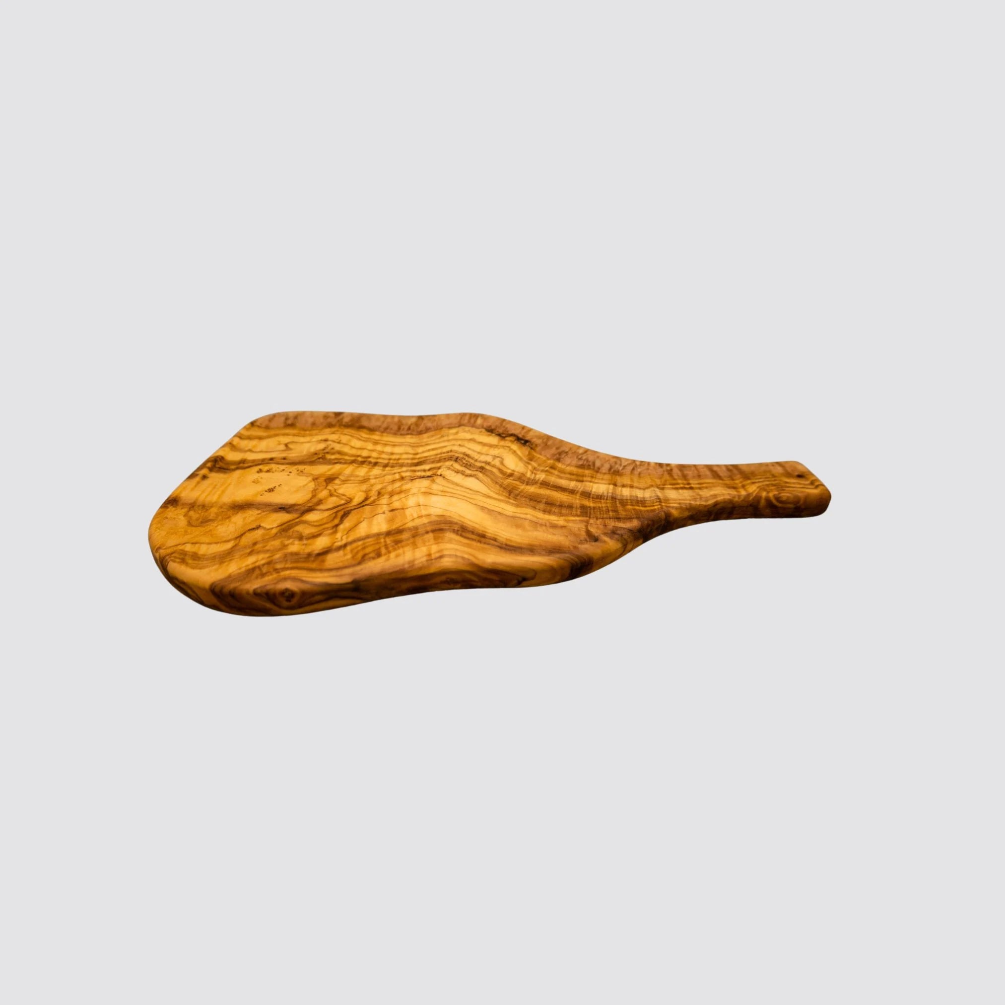 Angled view of a rustic olive wood serving board, emphasizing its organic shape and wood texture on a plain white background.