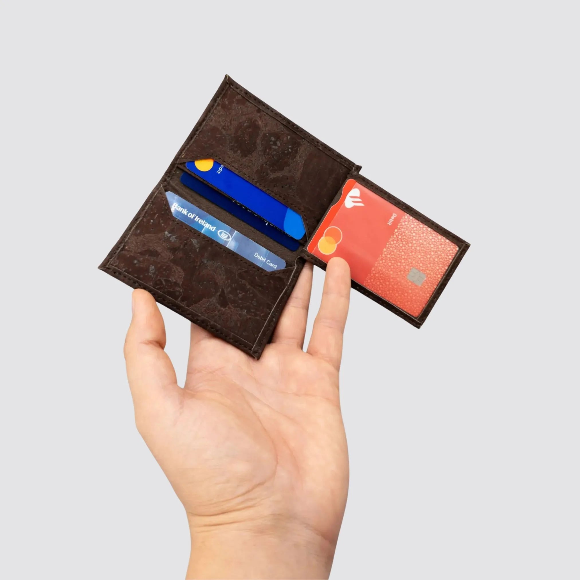 Open view of the cork cardholder held by a hand, displaying 4 card slots and an ID pocket for streamlined organization.