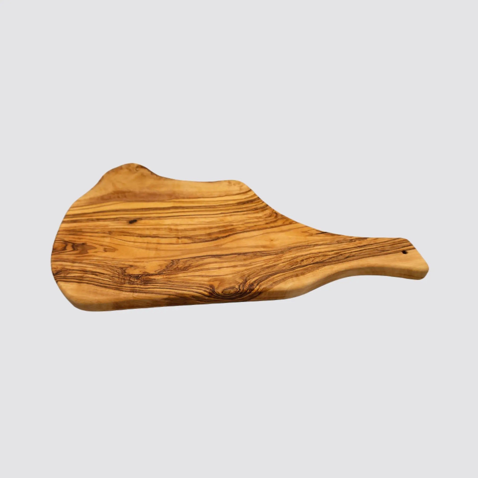 Angled view of a rustic olive wood charcuterie board, emphasizing its organic edges and polished finish on a plain white background.