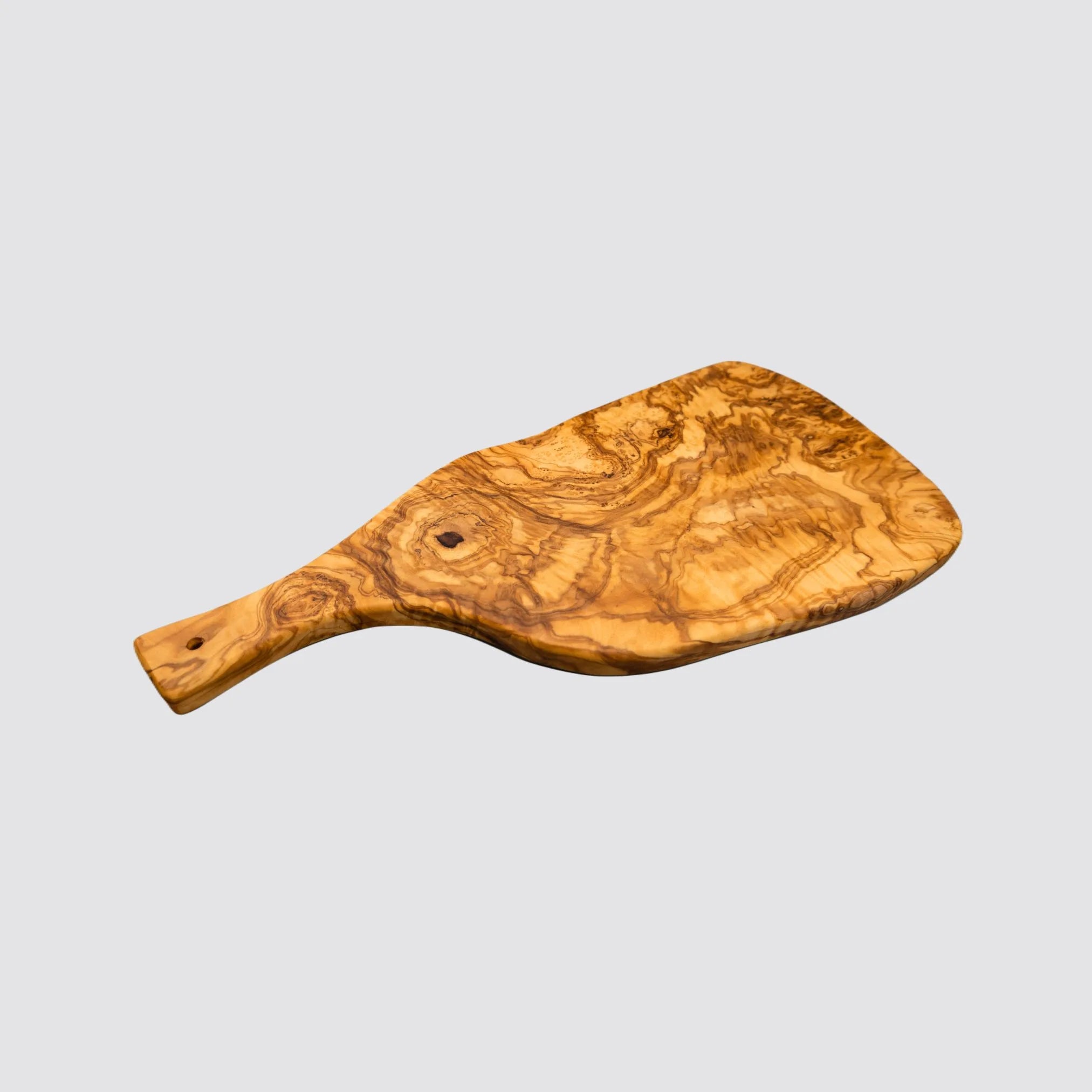 Serving and cutting board with handle made from sustainably sourced olive wood on a plain background.