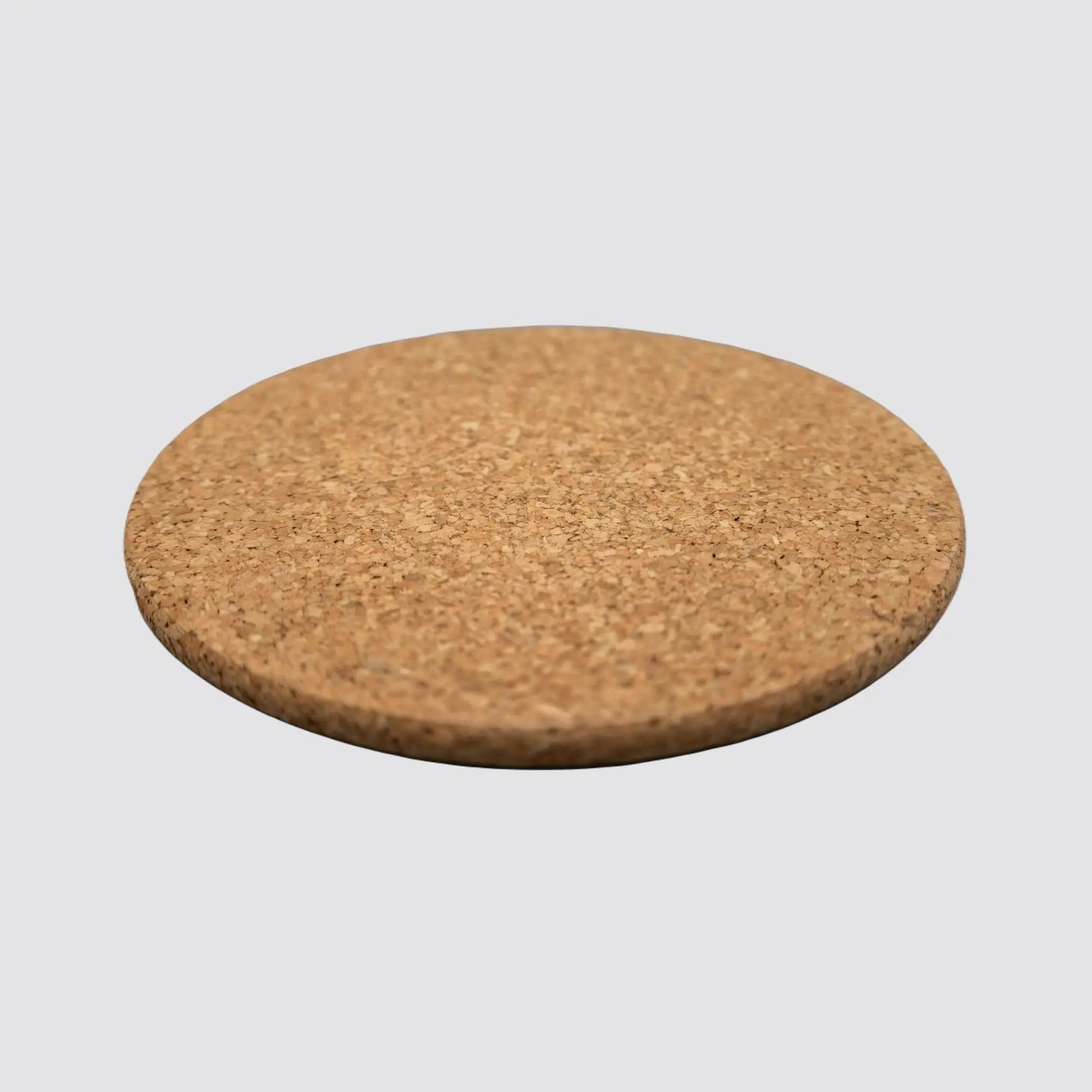 Angled view of a sustainable round cork placemat, showcasing its smooth surface and commitment to environmentally conscious living on a plain white background.