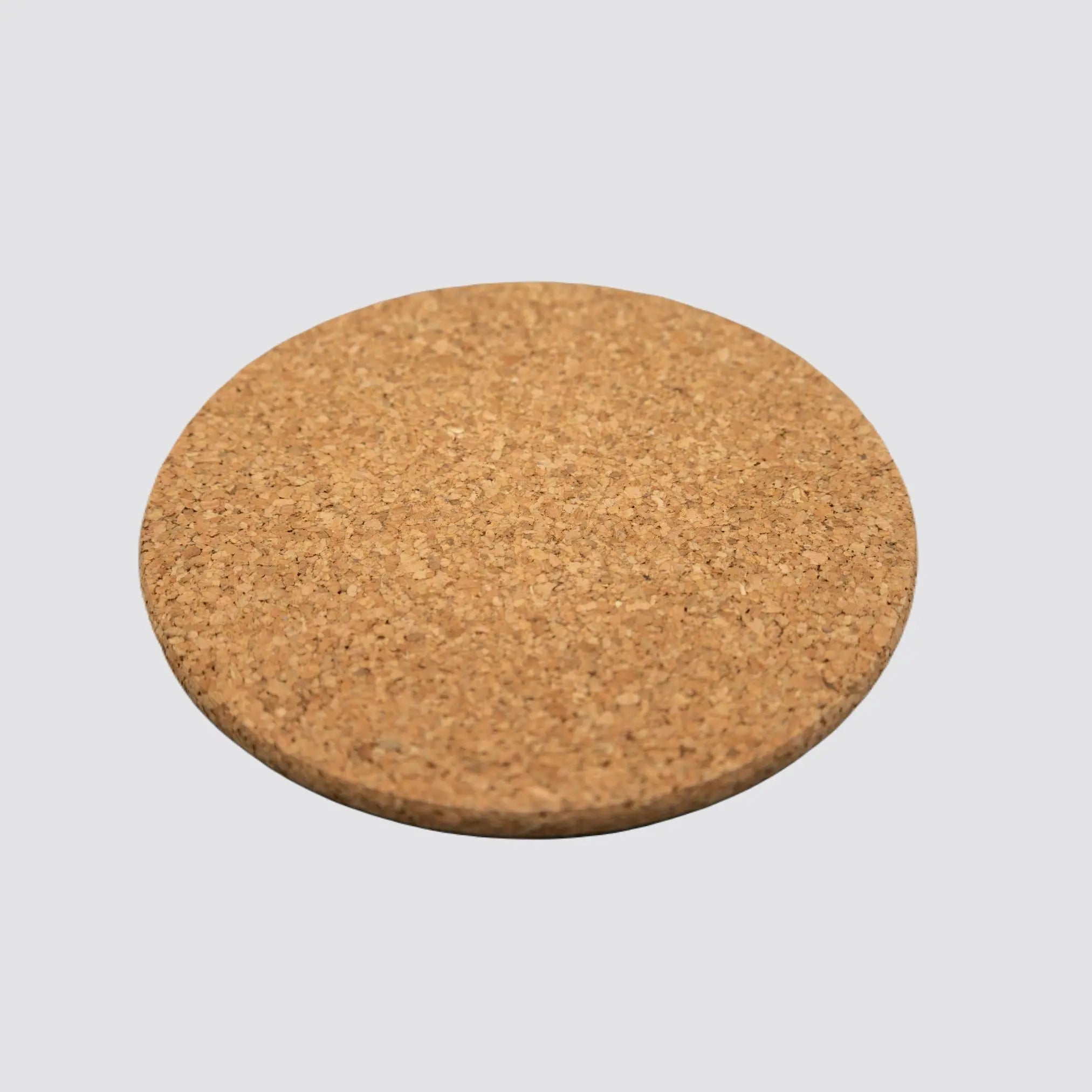 Side view of a sustainable round cork placemat, highlighting its durable thickness and natural, eco-conscious materials on a plain white background.