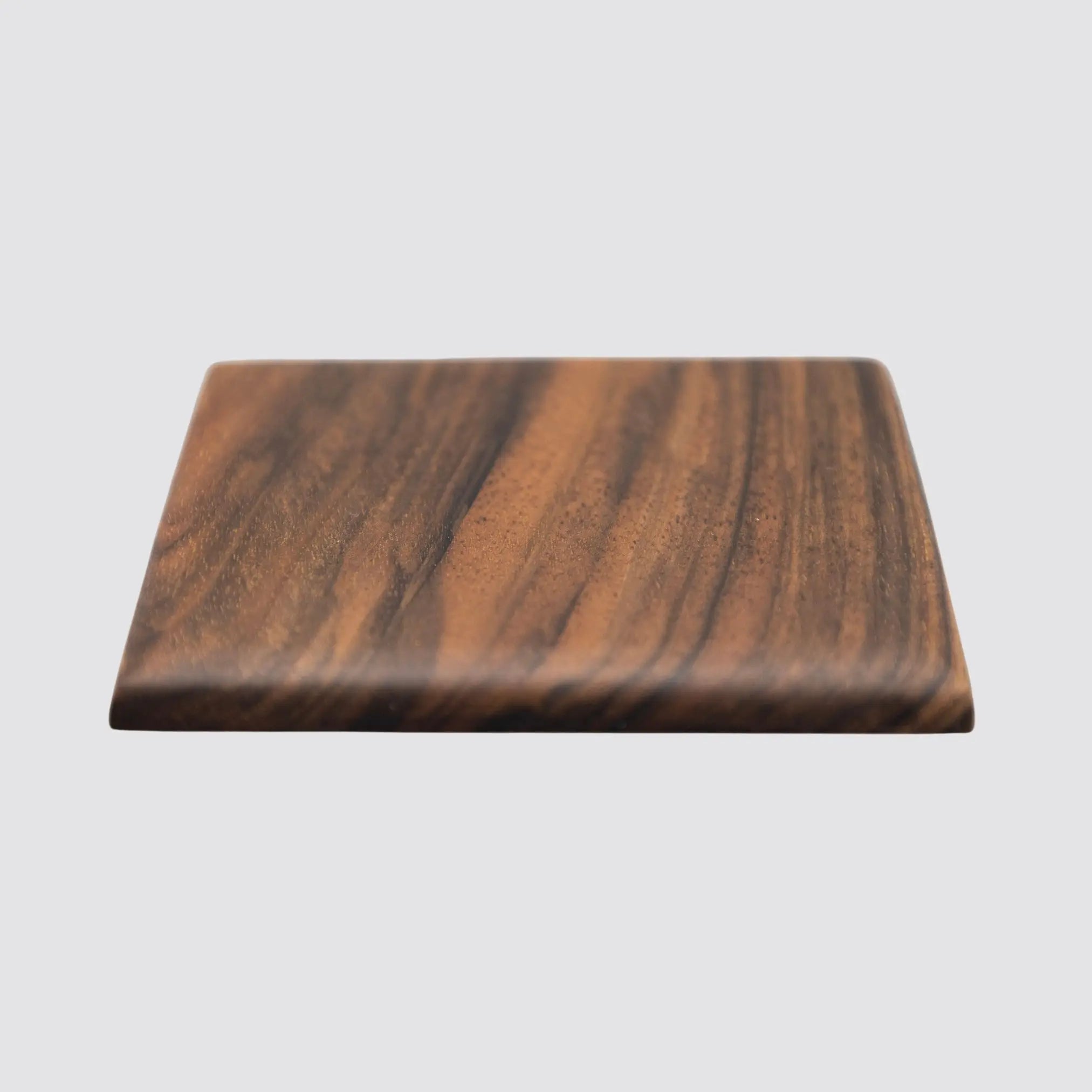 Angled view of a single walnut coaster, emphasizing its durable design and rich natural wood tones.