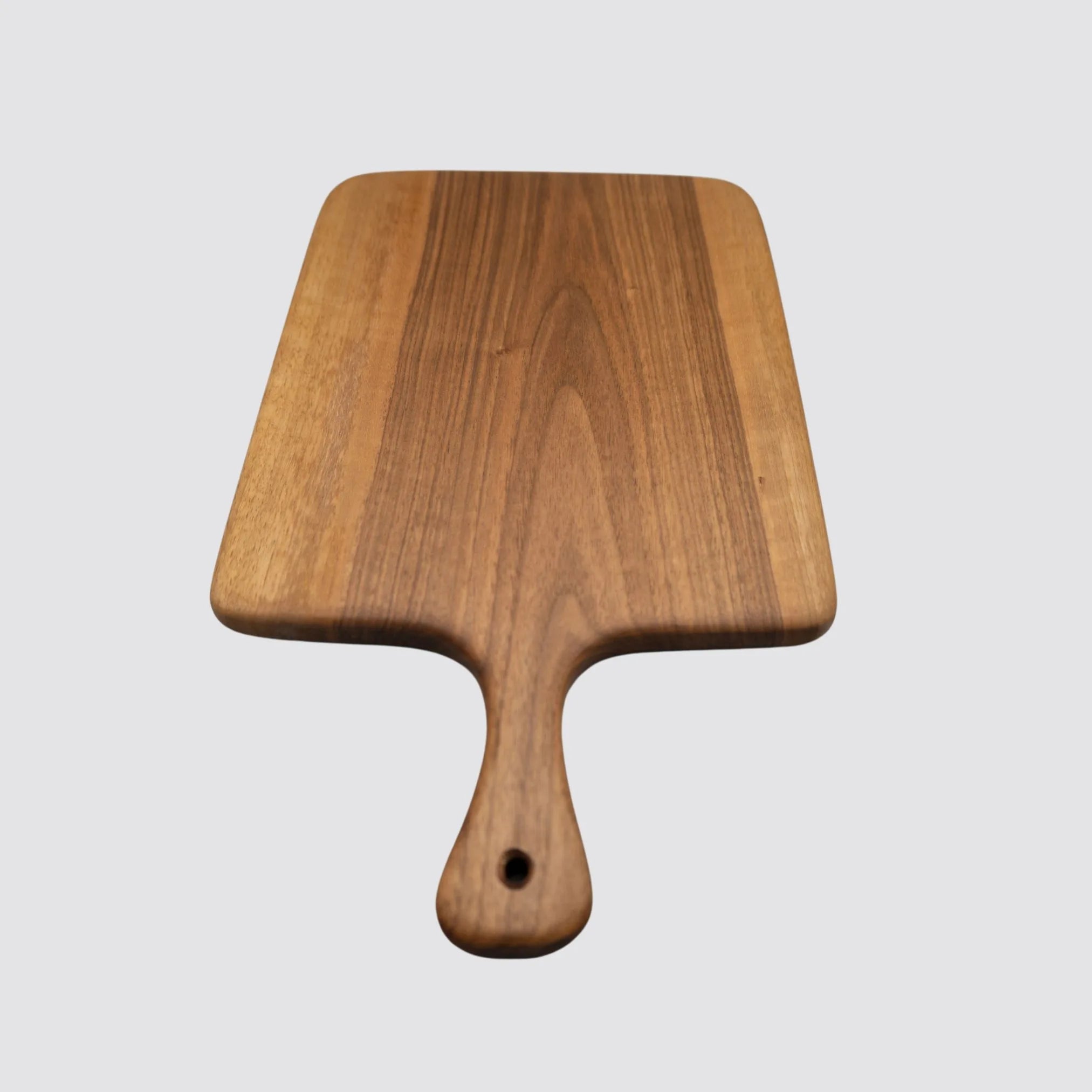 Walnut cutting board featuring a handle, ideal for serving and easy handling.
