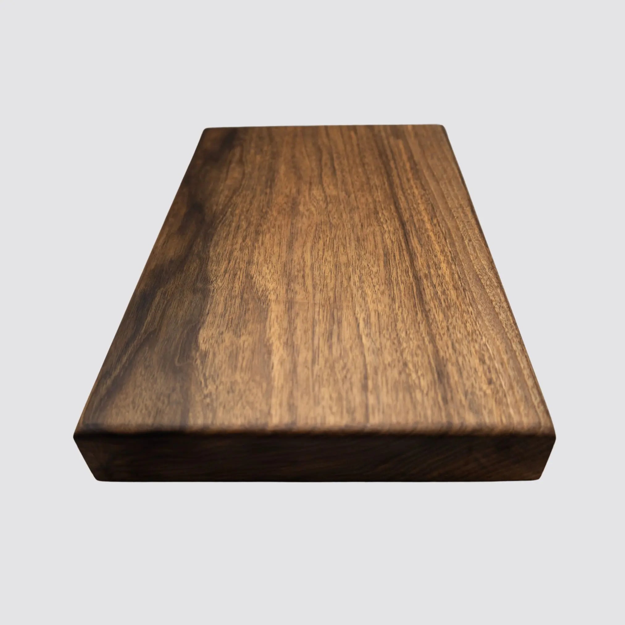Walnut cutting board displayed on a light background, emphasizing rich wood grain.