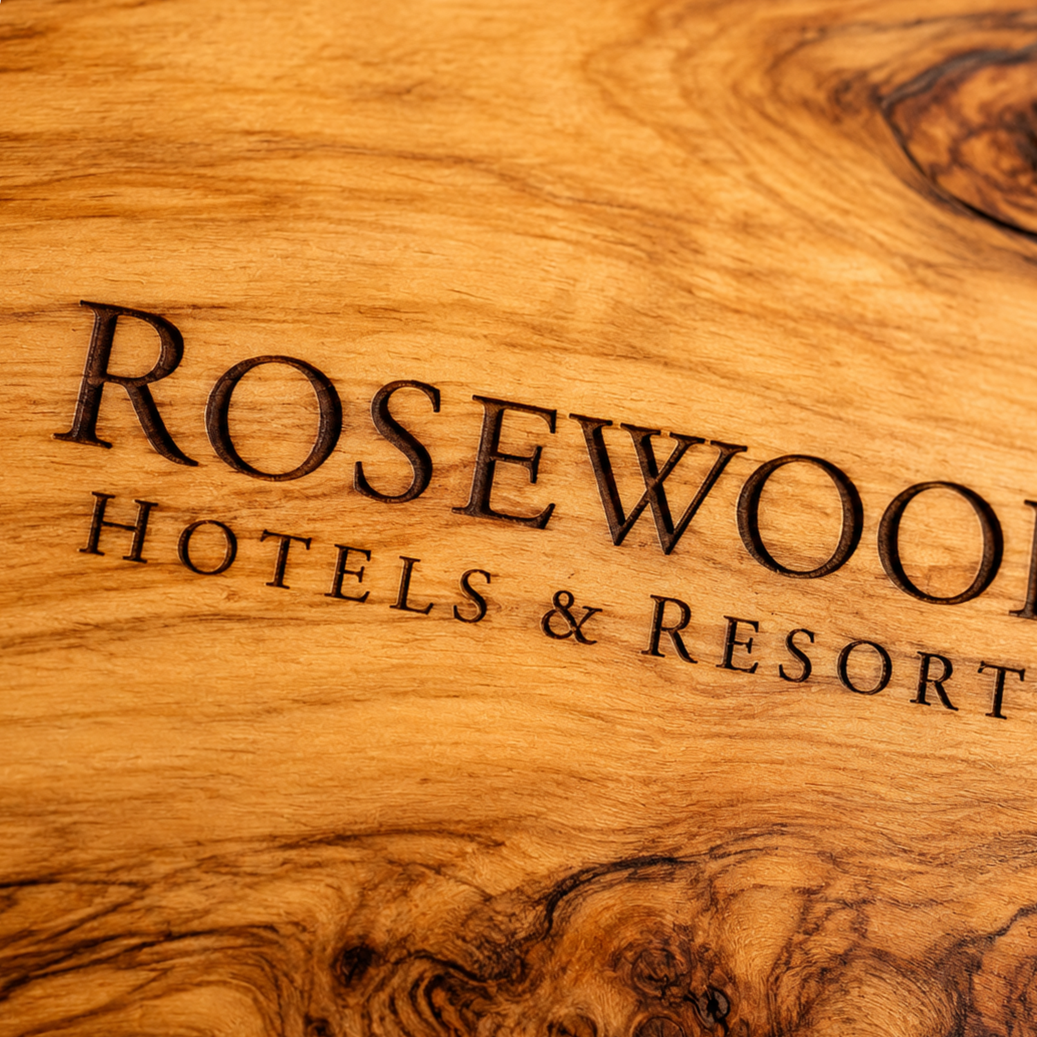 The logo of Rosewood Hotels engraved on olive wood