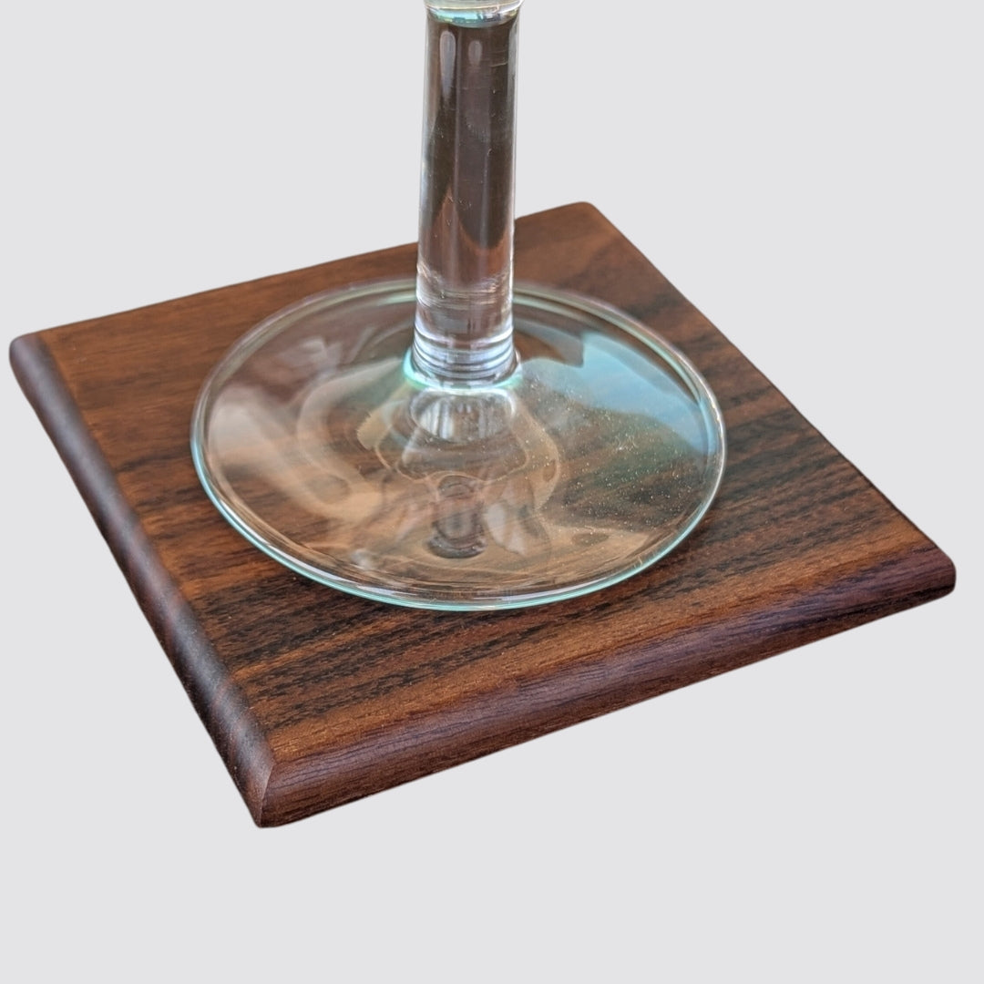 Clear glass on a wooden walnut coaster with a plain background