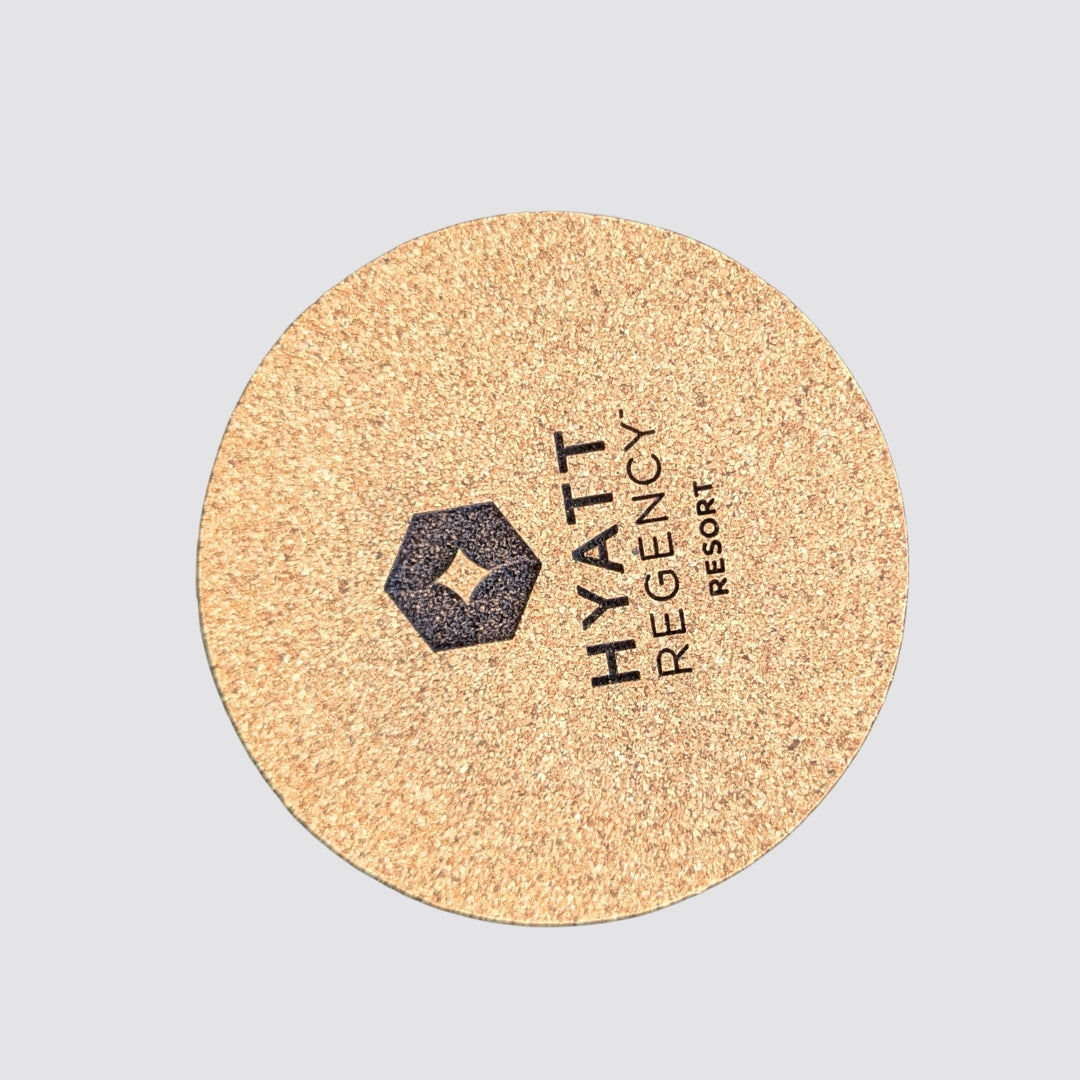 Round cork coaster with Hyatt Regency Resort logo on a light gray background