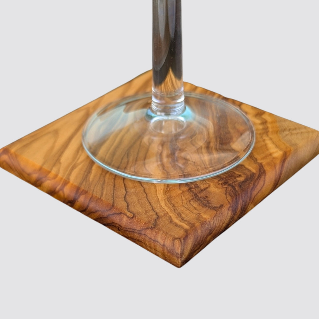 Wooden olive coaster with a glass on a white background